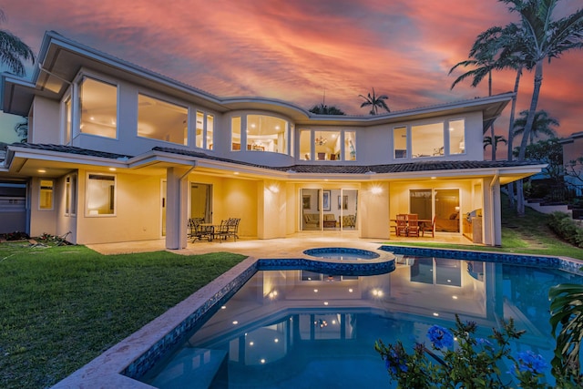 back of property at dusk with a yard, a patio area, stucco siding, and outdoor dining area
