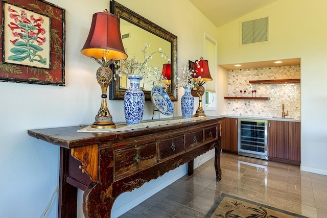 bar with lofted ceiling, beverage cooler, visible vents, a sink, and wet bar