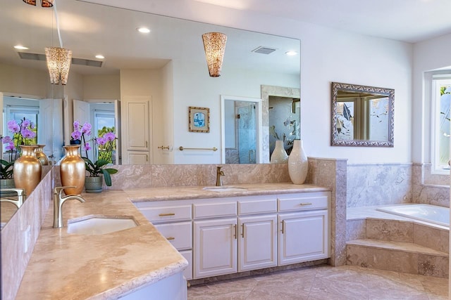 bathroom with double vanity, visible vents, a garden tub, and a sink