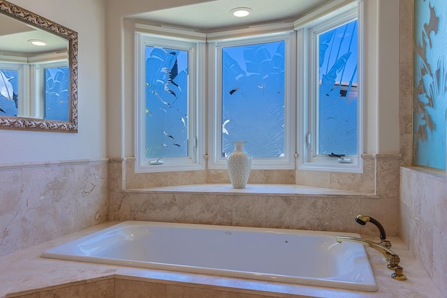 bathroom featuring a bath, wainscoting, and plenty of natural light