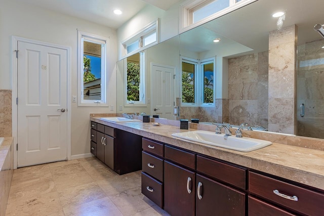 full bathroom featuring double vanity, baseboards, a tile shower, and a sink