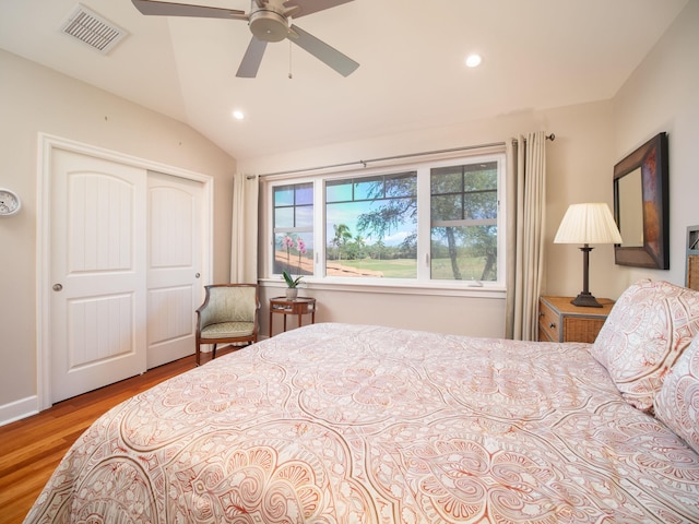 bedroom featuring light wood-type flooring, vaulted ceiling, a closet, and ceiling fan