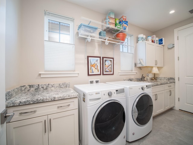 laundry area featuring cabinets, washer and clothes dryer, and sink