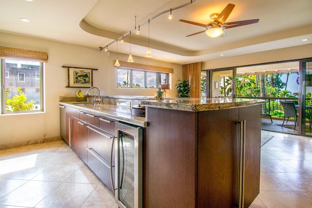 kitchen featuring stone countertops, dishwasher, sink, wine cooler, and a raised ceiling