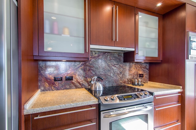 kitchen with stainless steel appliances, tasteful backsplash, and light stone counters