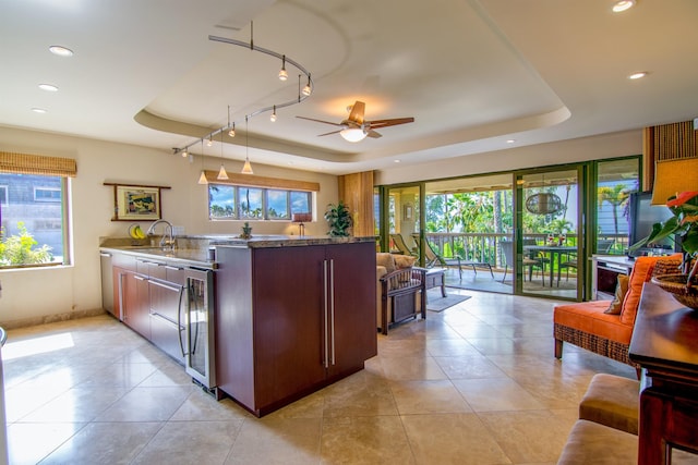 kitchen featuring sink, a tray ceiling, plenty of natural light, and beverage cooler