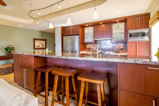 kitchen featuring light stone counters, appliances with stainless steel finishes, decorative light fixtures, and backsplash