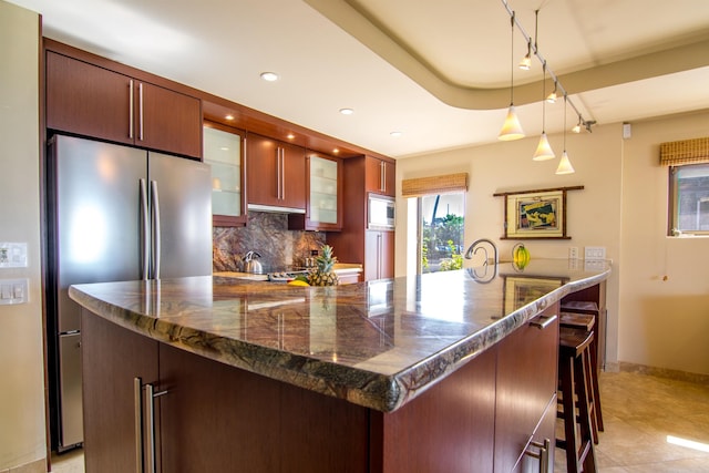 kitchen featuring appliances with stainless steel finishes, pendant lighting, tasteful backsplash, a kitchen breakfast bar, and light tile patterned floors