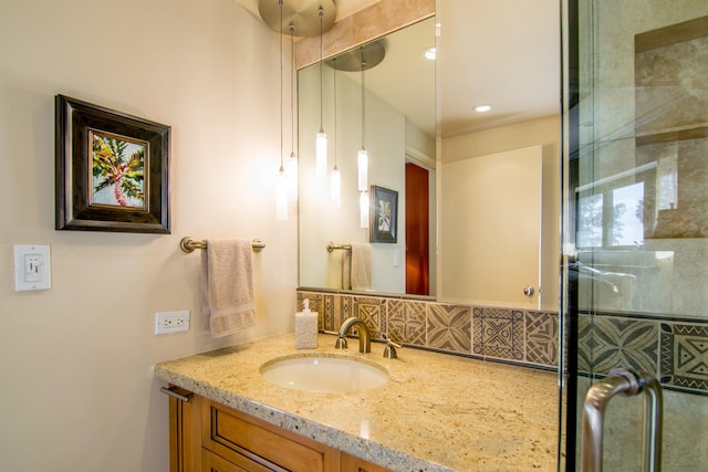 bathroom with vanity, a shower with shower door, and decorative backsplash