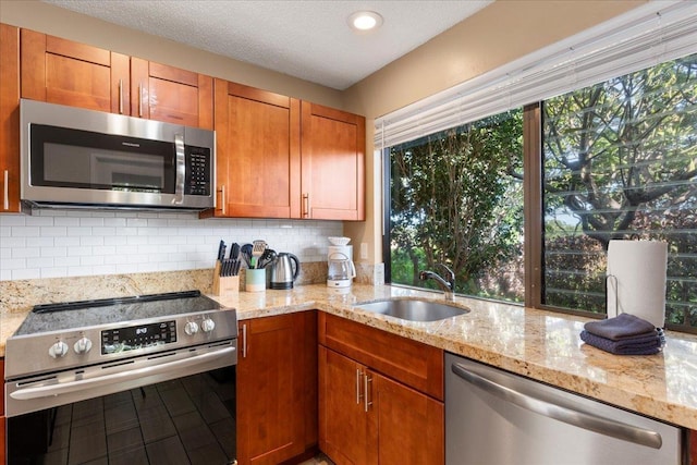 kitchen featuring backsplash, light stone countertops, a healthy amount of sunlight, and appliances with stainless steel finishes