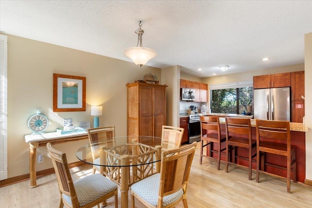 dining area with a textured ceiling and light wood-type flooring