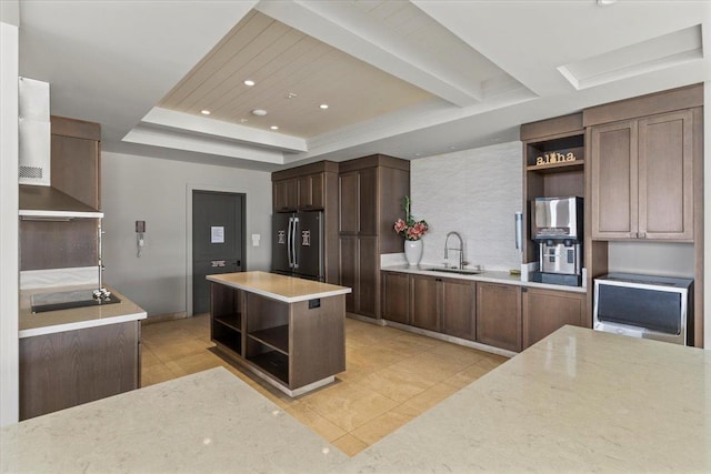 kitchen featuring a kitchen island, sink, stainless steel fridge, light tile patterned floors, and a tray ceiling