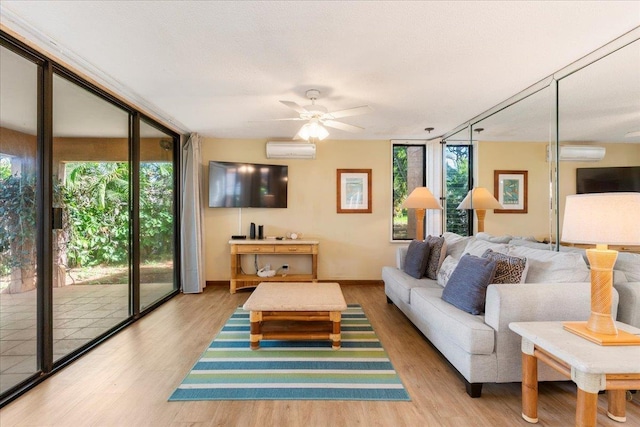 living room featuring ceiling fan, a wall of windows, a wall unit AC, and light hardwood / wood-style floors