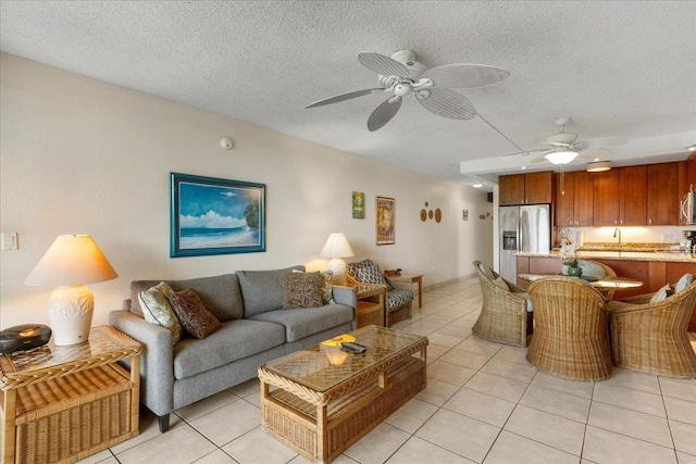 living area featuring light tile patterned floors, a ceiling fan, and a textured ceiling