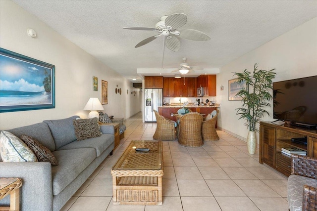living area with a textured ceiling, ceiling fan, and light tile patterned floors
