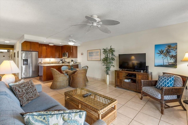 living room with light tile patterned floors, baseboards, ceiling fan, and a textured ceiling