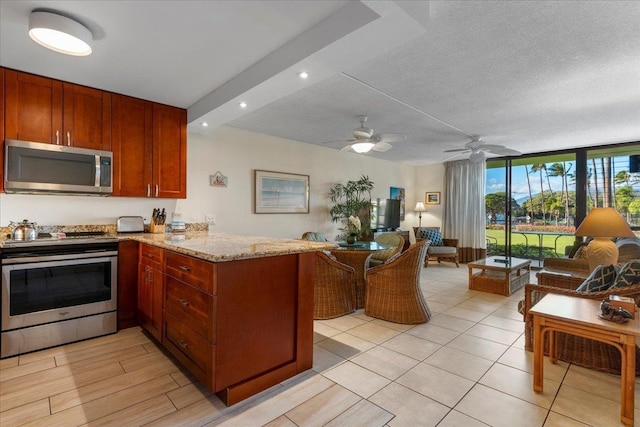 kitchen featuring light stone countertops, stainless steel appliances, open floor plan, a peninsula, and expansive windows