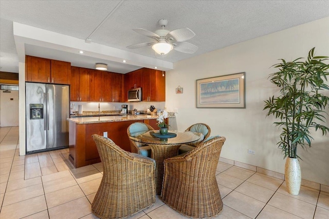dining area featuring a textured ceiling, ceiling fan, and light tile patterned floors