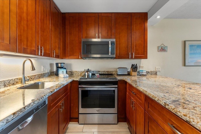 kitchen featuring a sink, light stone counters, stainless steel appliances, and recessed lighting