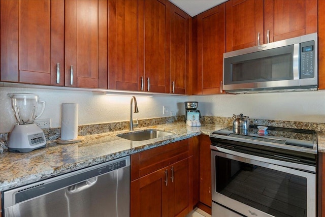 kitchen featuring stainless steel appliances, light stone counters, and a sink