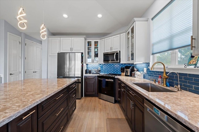 kitchen featuring a sink, stainless steel appliances, backsplash, and white cabinetry