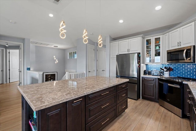 kitchen with decorative backsplash, white cabinets, light wood-type flooring, and stainless steel appliances