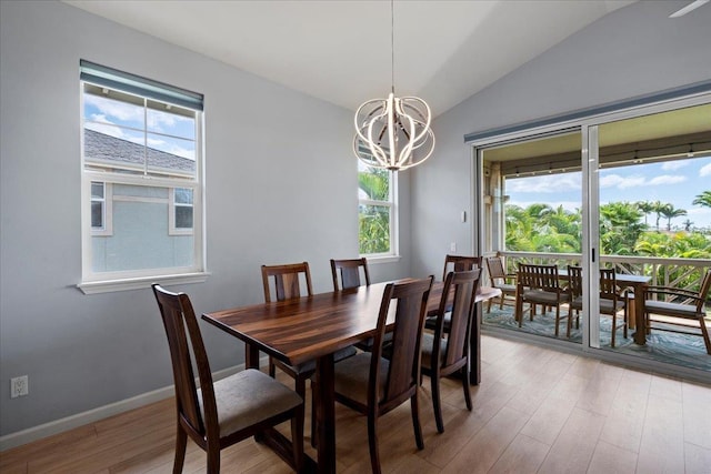 dining space featuring a chandelier, light wood-style flooring, a healthy amount of sunlight, and vaulted ceiling