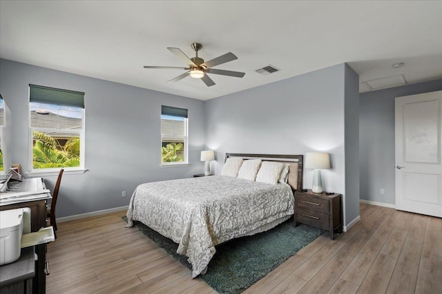 bedroom with baseboards, multiple windows, and light wood-style floors