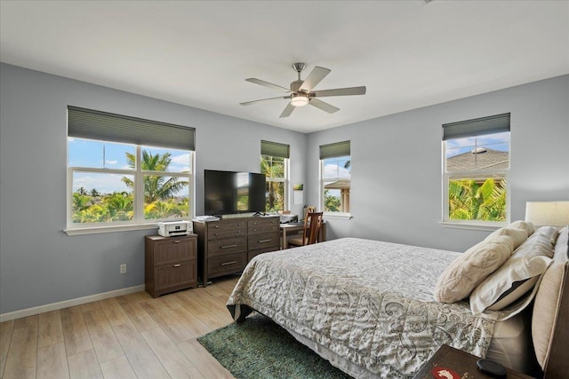 bedroom with a ceiling fan, light wood-style floors, and baseboards