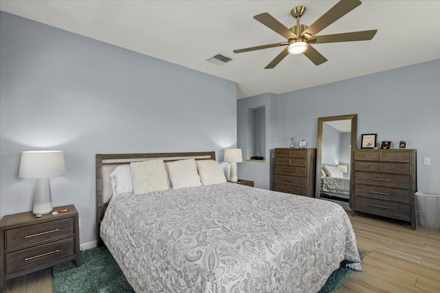 bedroom featuring baseboards, wood finished floors, visible vents, and ceiling fan