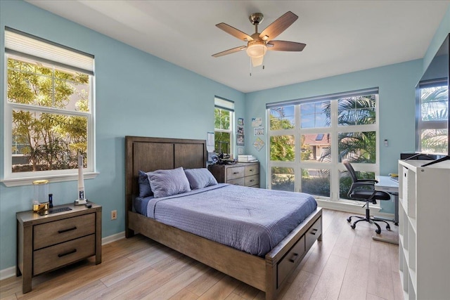 bedroom featuring baseboards, light wood-style floors, and a ceiling fan