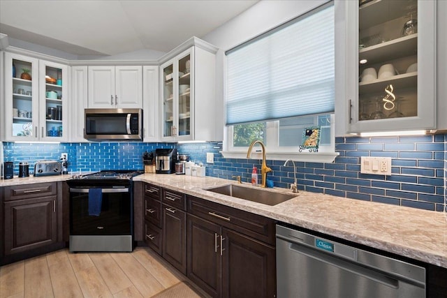 kitchen with a sink, white cabinetry, stainless steel appliances, light countertops, and dark brown cabinets