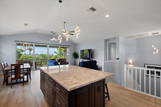 kitchen with visible vents, open floor plan, light wood-style floors, lofted ceiling, and dark brown cabinets