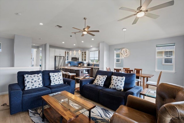 living room featuring visible vents, ceiling fan, lofted ceiling, recessed lighting, and light wood-style floors