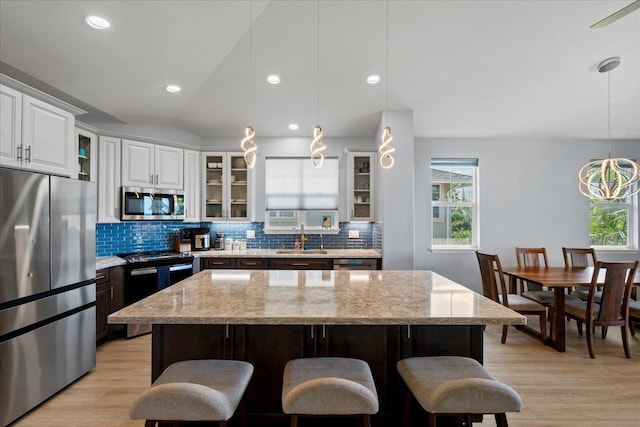 kitchen featuring backsplash, glass insert cabinets, appliances with stainless steel finishes, and a sink