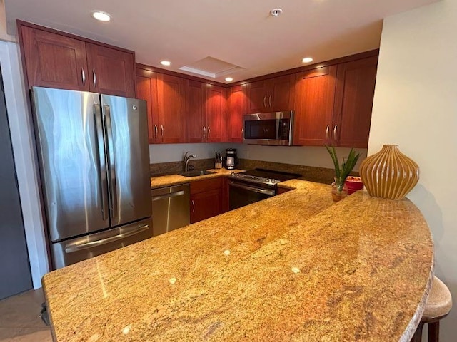 kitchen featuring light stone countertops, stainless steel appliances, sink, a kitchen breakfast bar, and kitchen peninsula