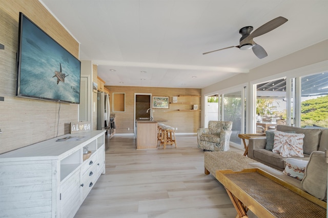 living room with ceiling fan, sink, and light hardwood / wood-style flooring