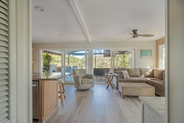 sunroom featuring ceiling fan, beam ceiling, and a wealth of natural light