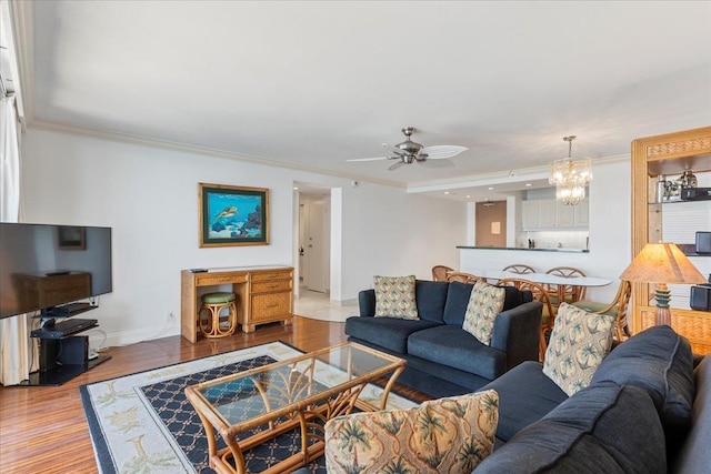 living room featuring ceiling fan with notable chandelier, ornamental molding, and wood-type flooring