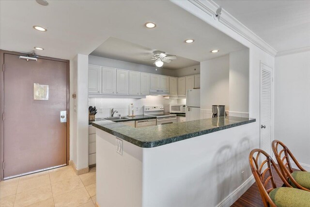 kitchen featuring white appliances, white cabinets, tasteful backsplash, kitchen peninsula, and ceiling fan