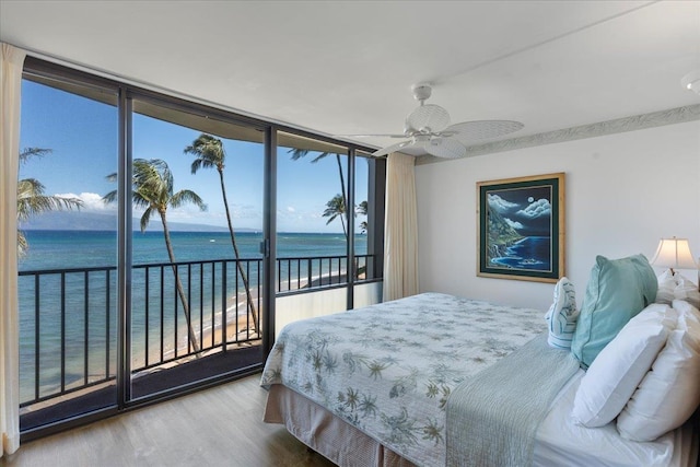 bedroom with expansive windows, ceiling fan, a water view, and access to outside