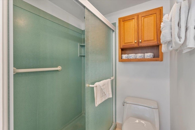 bathroom featuring toilet and a shower with door