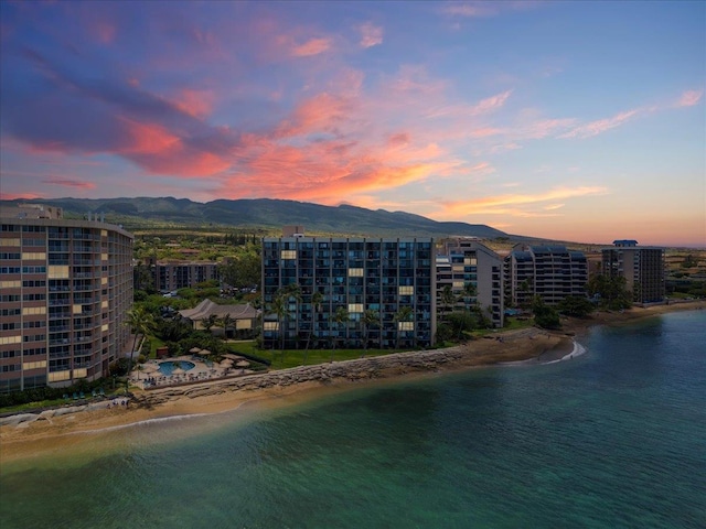 aerial view at dusk featuring a water and mountain view