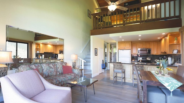 living room with ceiling fan, a high ceiling, and dark hardwood / wood-style flooring