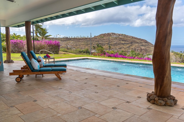 view of swimming pool featuring pool water feature, a mountain view, and a patio