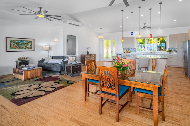 dining room featuring an AC wall unit, sink, vaulted ceiling, and light wood-type flooring