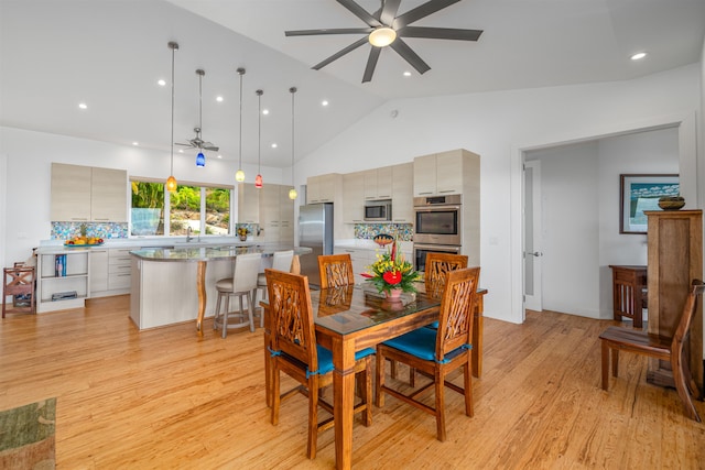 dining space featuring ceiling fan, light hardwood / wood-style floors, and vaulted ceiling