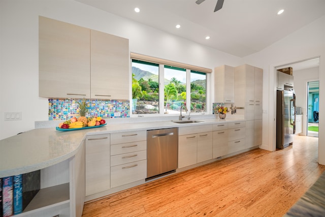 kitchen with vaulted ceiling, ceiling fan, light wood-type flooring, appliances with stainless steel finishes, and kitchen peninsula