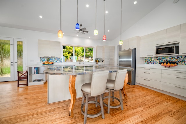 kitchen with decorative backsplash, ceiling fan, stainless steel appliances, and light hardwood / wood-style floors