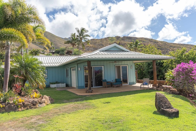 back of property with a mountain view, a yard, and a patio area